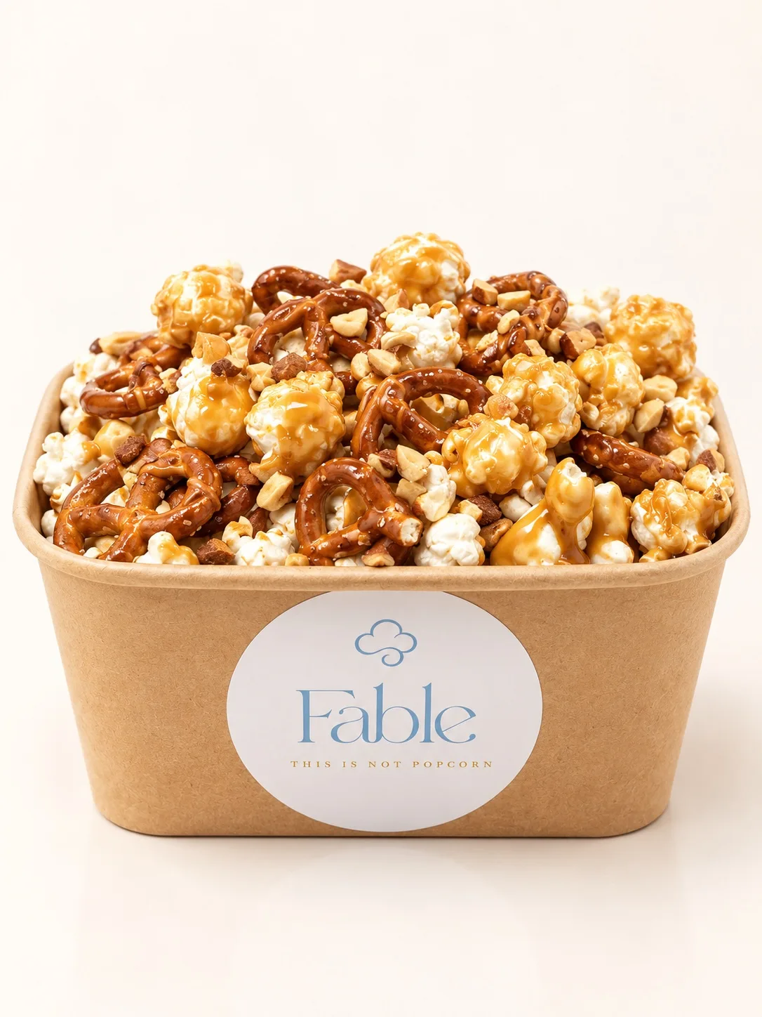 A kraft Fable tub piled high with golden drizzled popcorn and crunchy toppings.